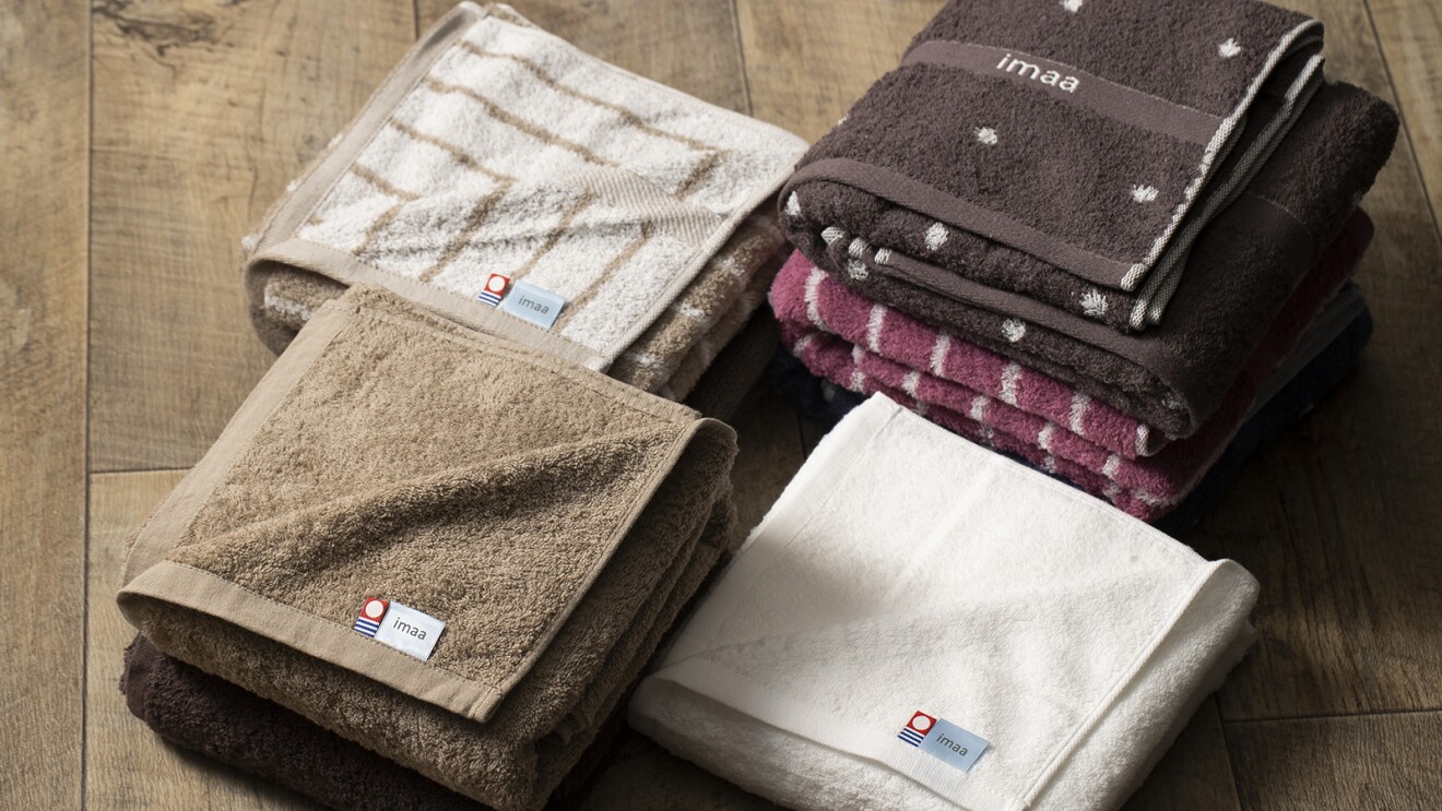 今治タオルのマーク（赤字に白い丸の下に青と白のストライプ）のタグが付いているさまざま色のタオル