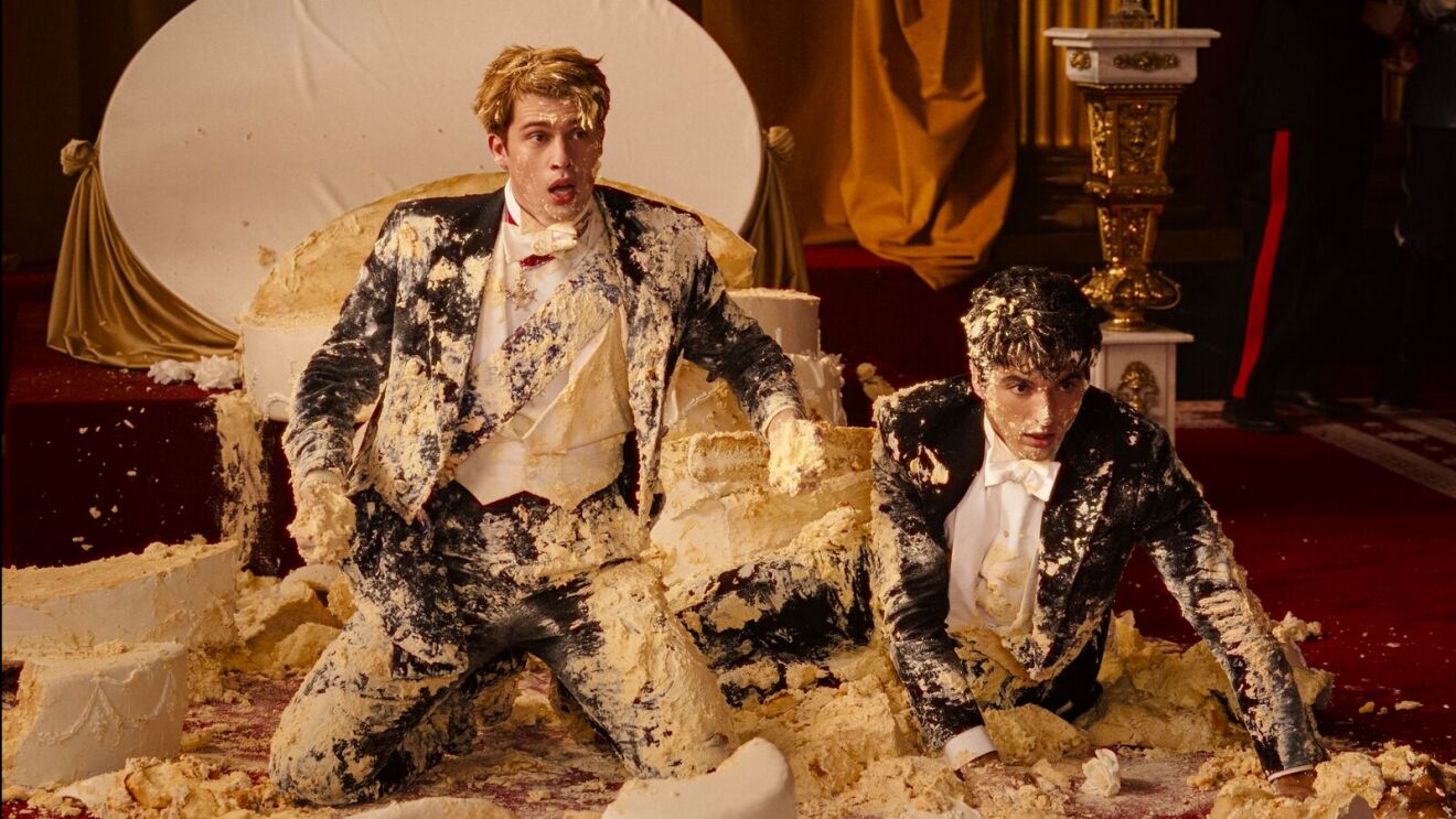 A scene of Red, White & Royal Blue with two men in formal attire covered in cake debris