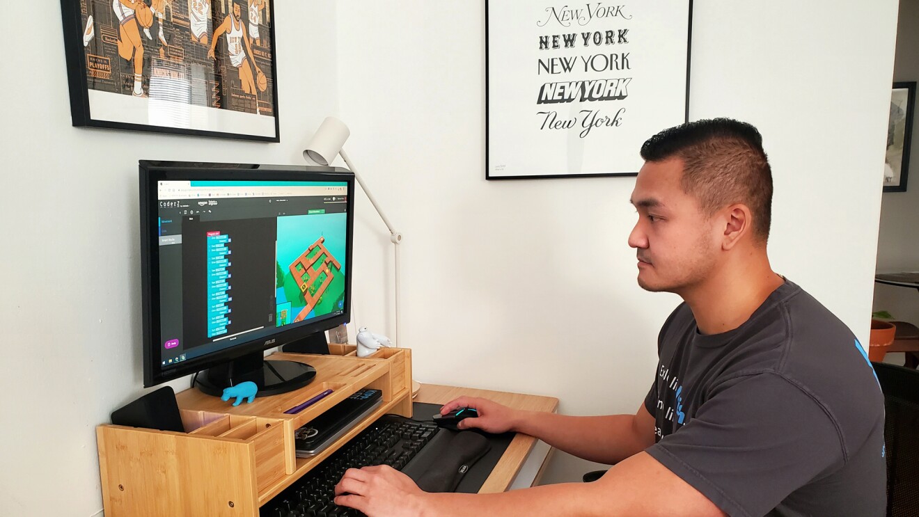 一个男人坐在一张桌子上,在电脑上工作。