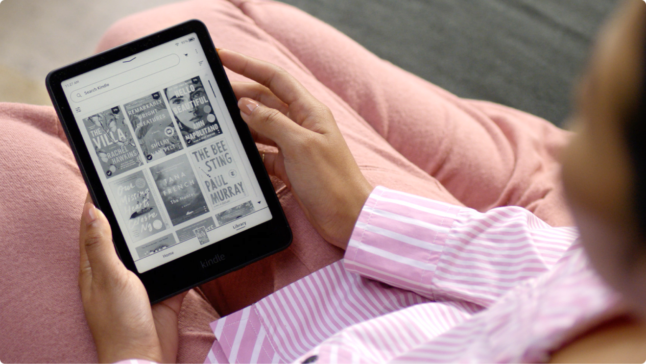 A woman dressed in pink holding a Kindle Paperwhite