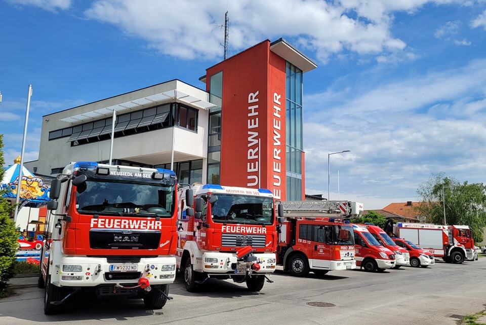 AWS in Österreich unterstützt blaulichtSMS. Das Bild zeigt mehrere Feuerwehrautos von einem Gebäude auf dem in weißer Schrift auf rotem Hintergrund das Wort "Feuerwehr" zu lesen ist.