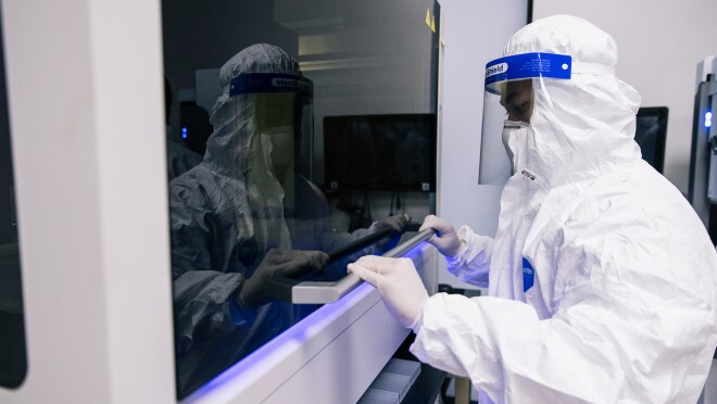 一个穿着个人防护装备的人关闭一件实验室设备。