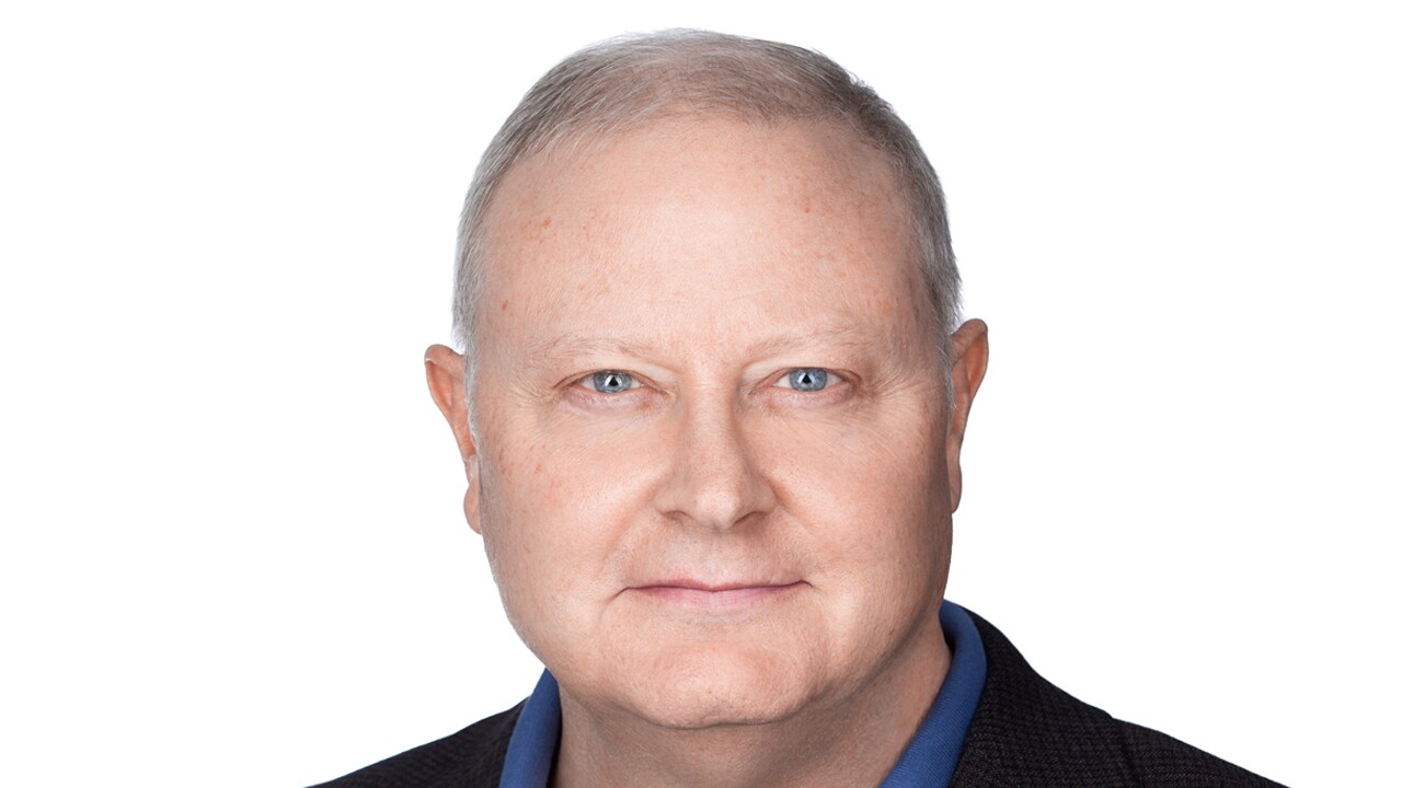 A headshot image of a man with a white background behind him. 