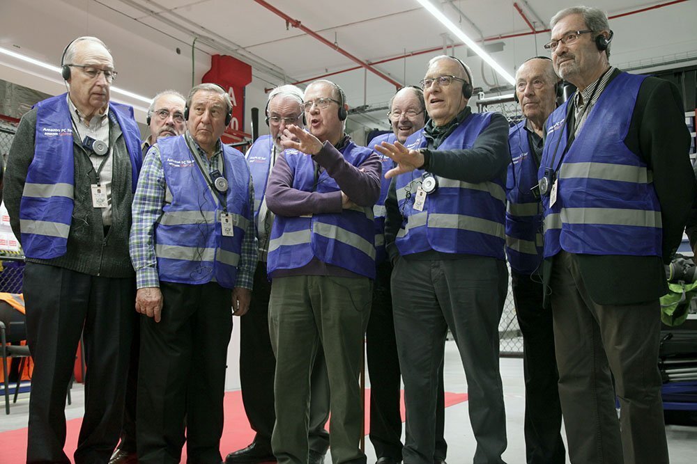Un grupo de ingenieros jubilados durante una visita al centro logístico. Todos ellos visten con chaleco azul.
