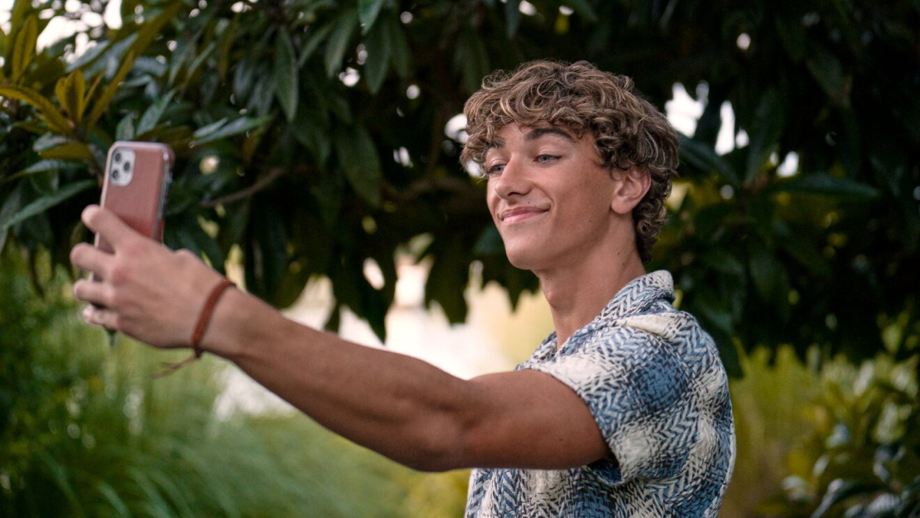 Casually dressed Jeremiah Fisher (Gavin Casalegno) capturing self-portrait in nature