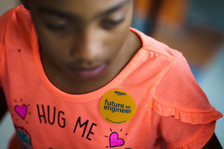 A young girl wearing an "Amazon Future Engineer" sticker on her shirt.