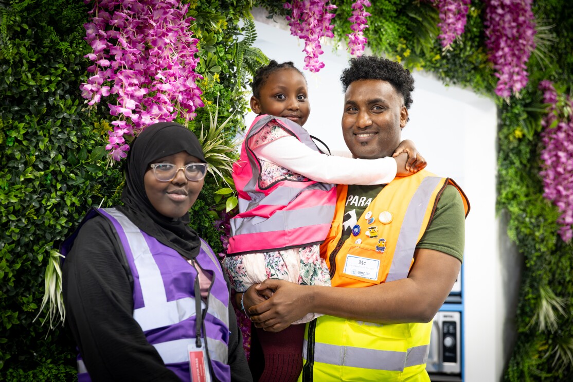 A man, a woman and a child are pictured in front of flowers