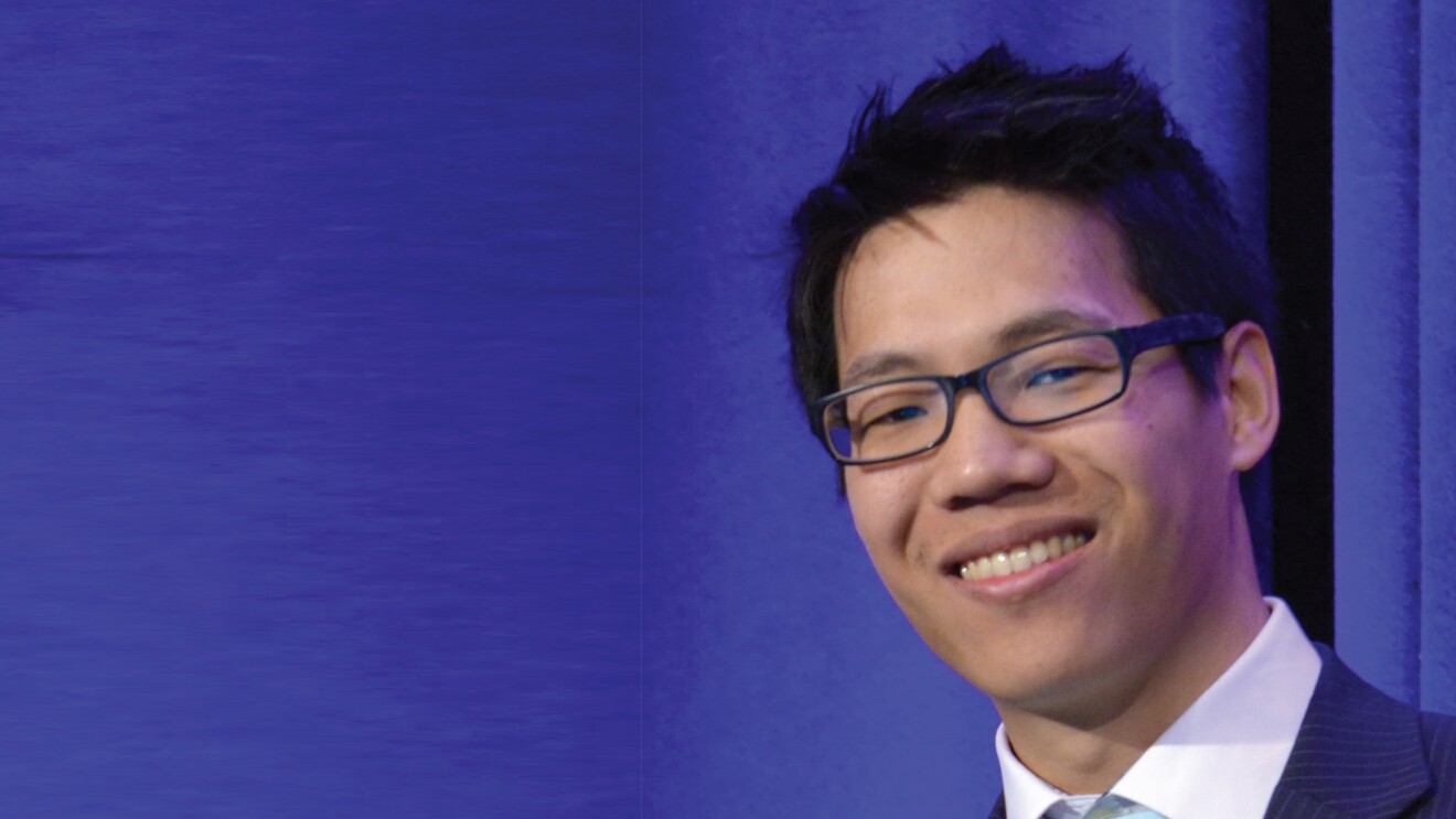 Headshot of William Lau in front of a blue curtain. 