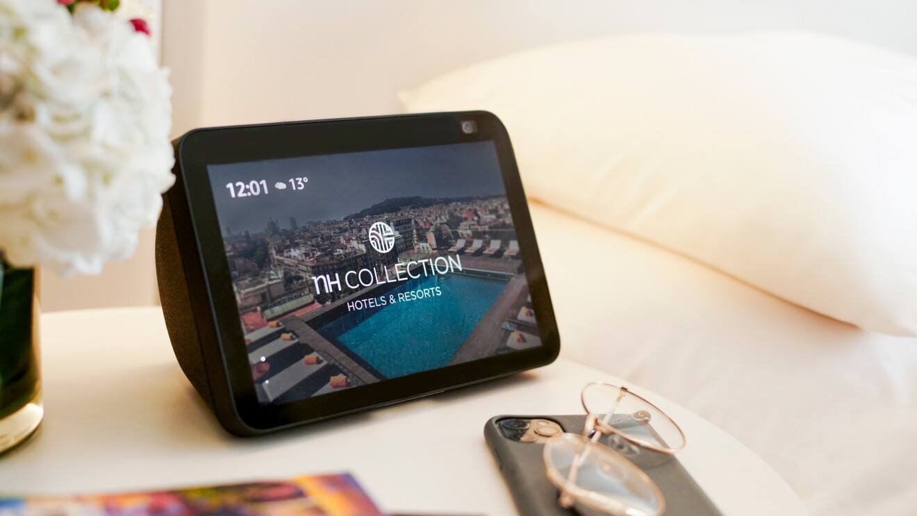 En una mesa de hotel hay un dipositivo de Amazon con Alexa incorporada.