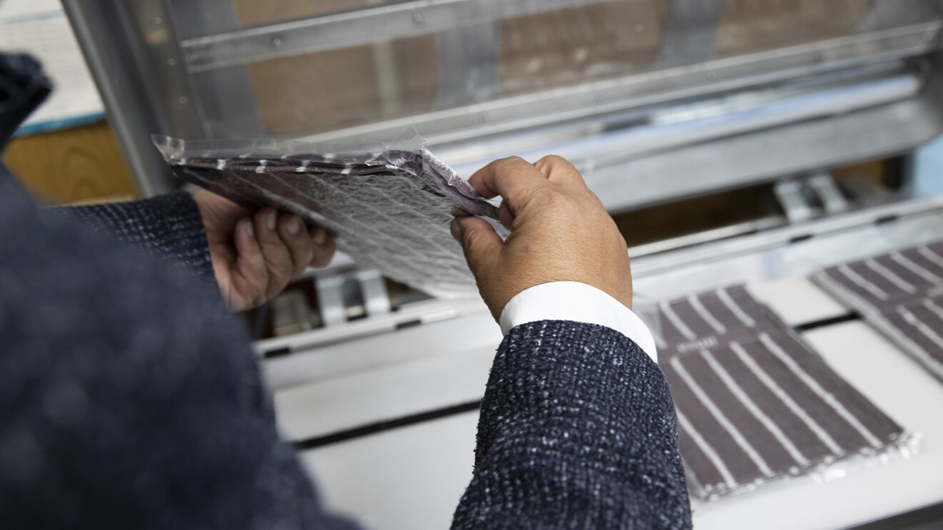 機械の前でタオルの断面を向けて両手で持つ男性の手