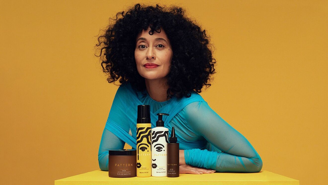 Woman in blue shirt displaying haircare line