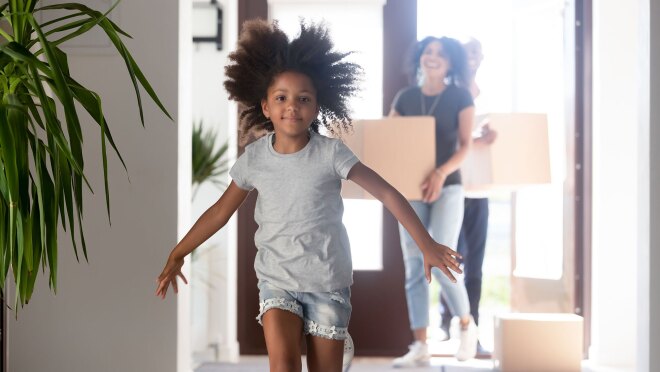 一个小女孩跑进了一所房子。在她身后,成年人抬着移动的箱子进了家。