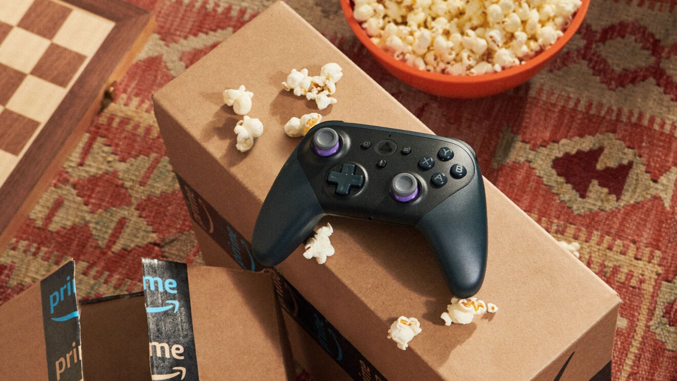 An image of two Amazon boxes, a black Luna remote and a red bowl of popcorn. 