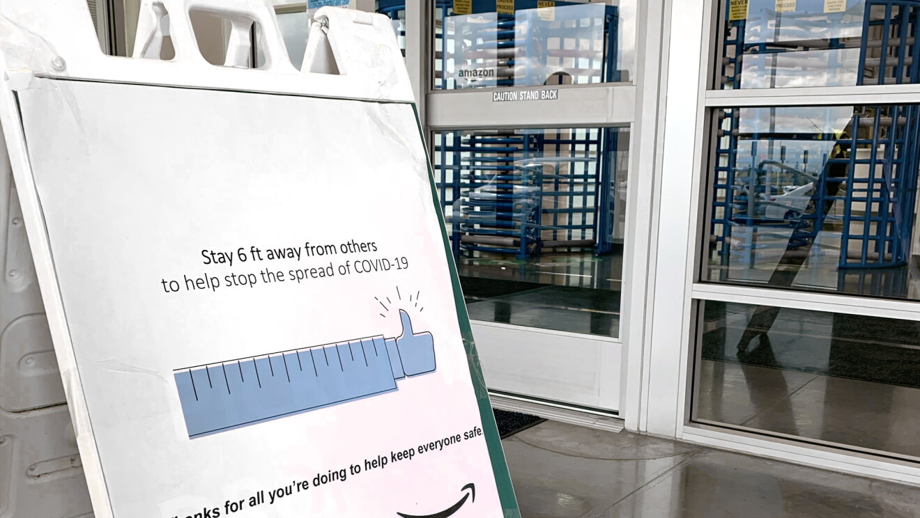 Oznakowanie przy wejściu do centrum realizacji zamówień Amazon, które mówi: „Trzymaj 6 stóp od innych, aby powstrzymać rozprzestrzenianie się COVID-19. Dziękujemy za wszystko, co robisz, aby wszyscy byli bezpieczni”.