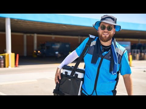 An image of an Amazon delivery driver wearing a bucket hat and carrying a cooler.