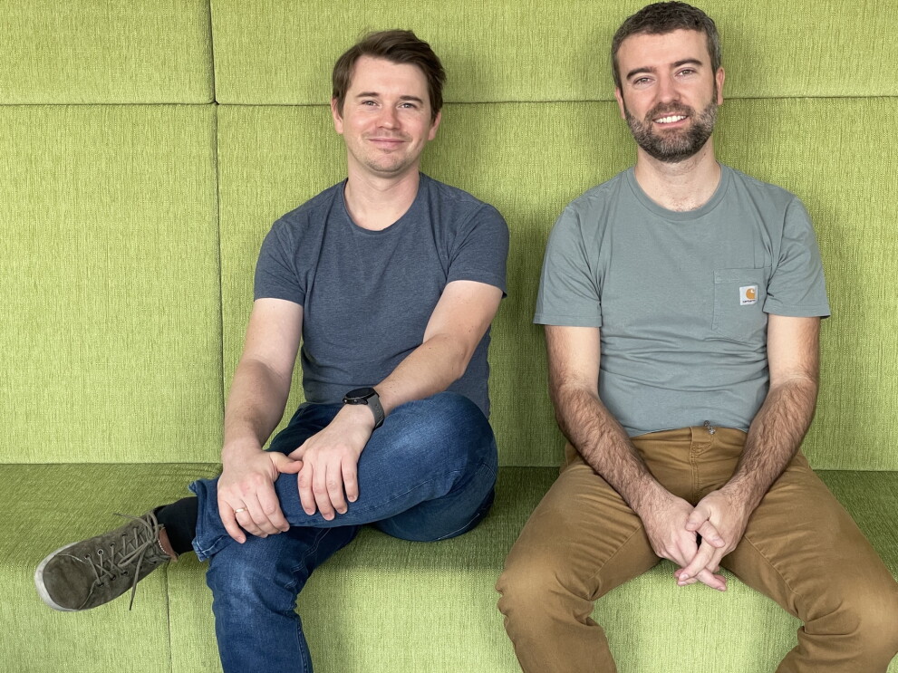 Die Vorarlberger Daniel Schlacher & Daniel Ender von D&D Living sitzend auf einer grünen Couch.