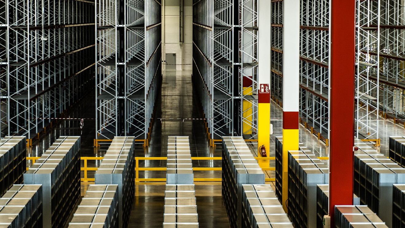 Imagen vertical del centro logísticos de Illescas. en primer plano aparecen estanterías para productos y al fondo estanterías mucho más altas para palés. 