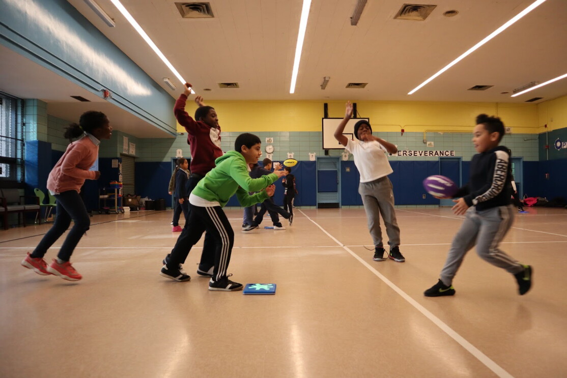 An image of children playing the game, Splat. They're jumping on small blue squares that react when they jump.