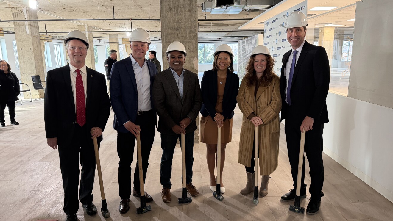 Six diverse professionals in hard hats at construction site