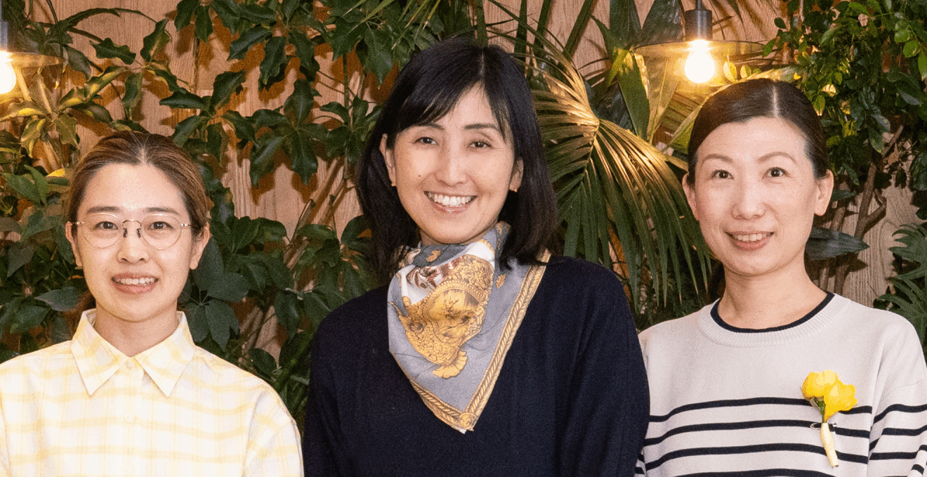 木の壁と観葉植物を背に、並んだ3人の女性。笑顔でこちらを見ている。