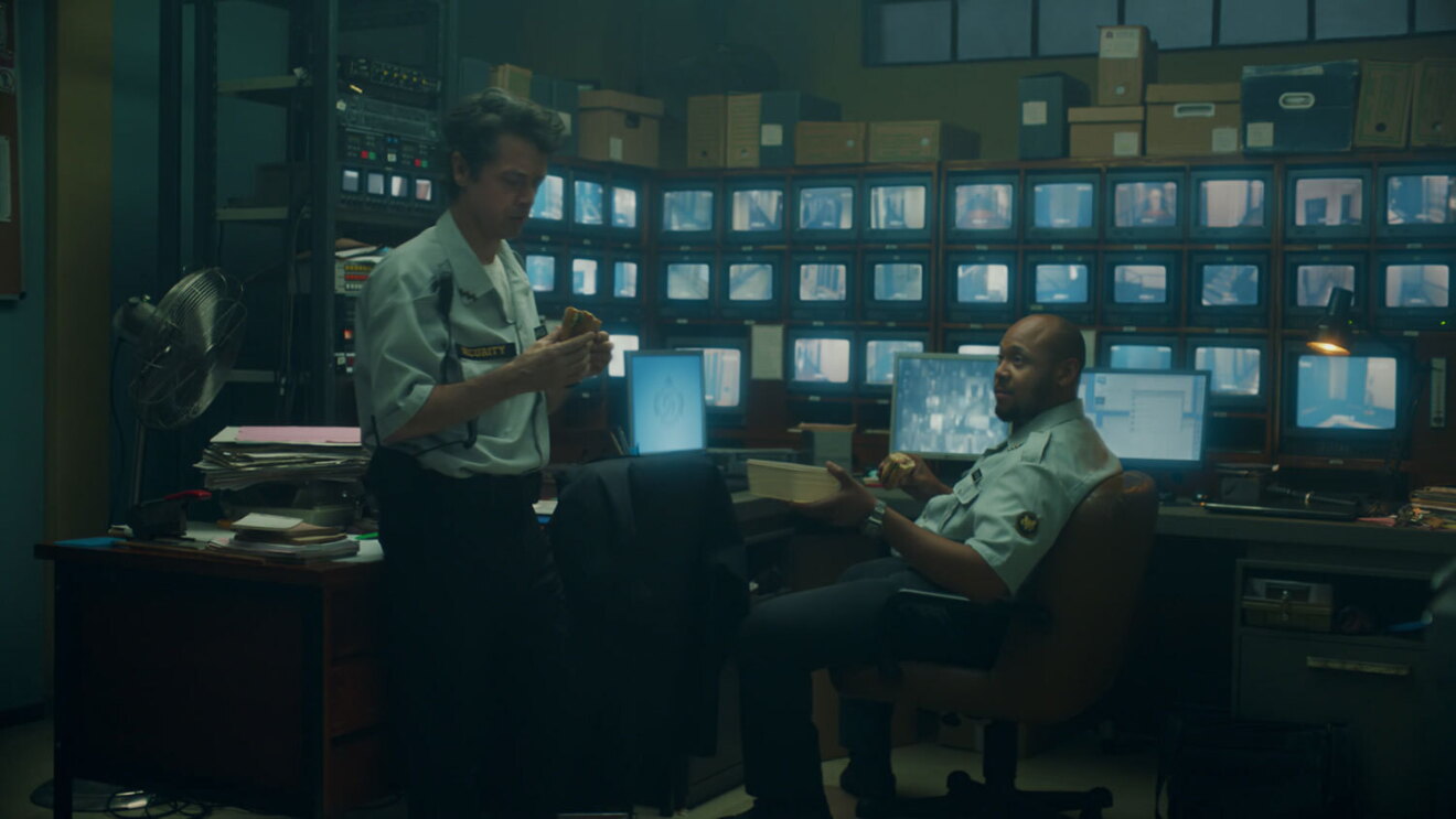 An screenshot image of a security guard in the security office during the Amazon Prime commercial where he becomes a chef.