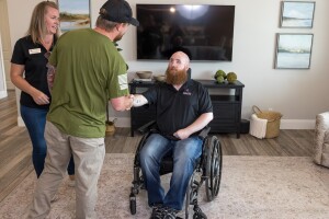 A photo of Matthew Williams, senior program manager on Amazon’s Global Military Affairs team, shaking hands with a U.S. veteran in a wheelchair in their home.