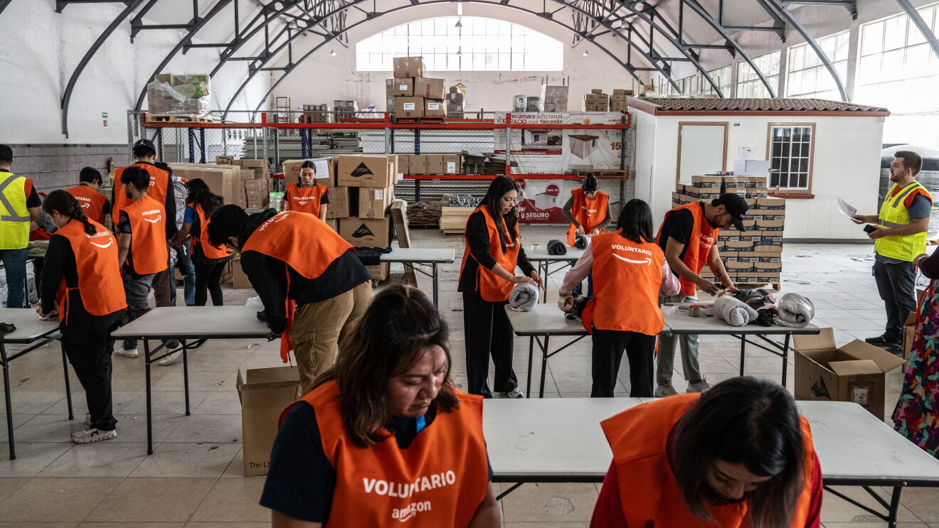 Disaster relief operations in Mexico City; Volunteers in orange vests sorting donations in large warehouse