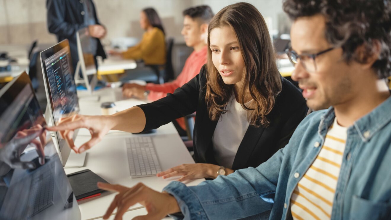 两个成年人工作的照片在电脑教室。他们指着监控内容。