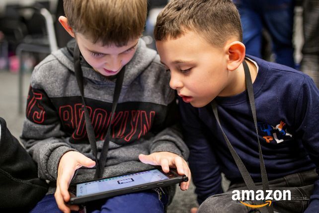 Two young boys play on a tablet device.