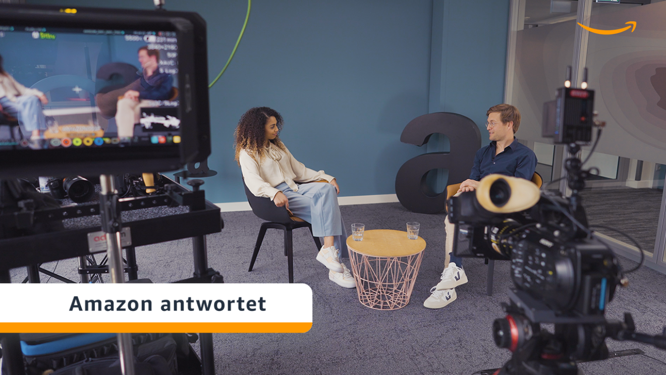 Ole und Cherifa sitzen in einem Amazon Büro und unterhalten sich. 
