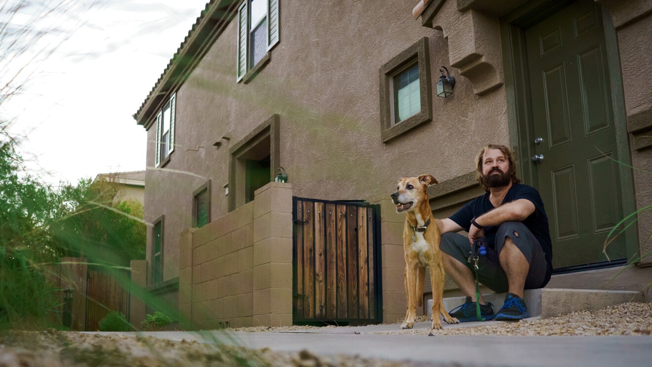 A dog and a man sitting on the doorstep of a home.