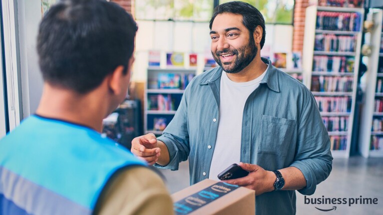Smiling man receiving package from Amazon delivery person in bookstore