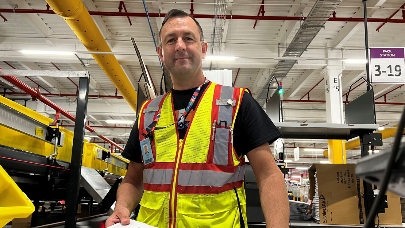 Former army officer and Amazon operations manager Keith Langan holds an Amazon package at the Kemps Creek fulfilment centre