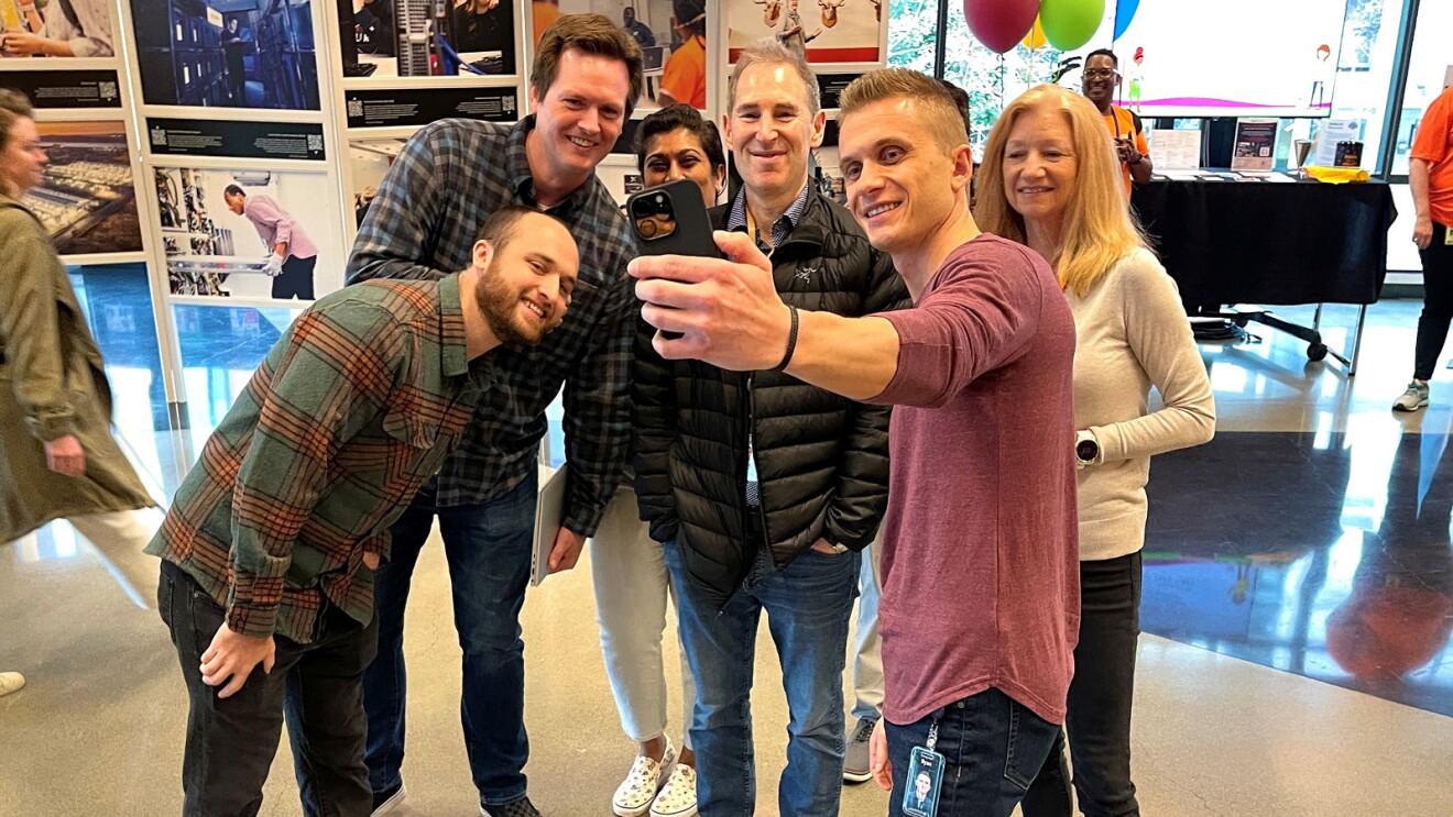 A photo of CEO Andy Jassy standing with three employees, taking a photo together at Amazon’s Seattle headquarters.