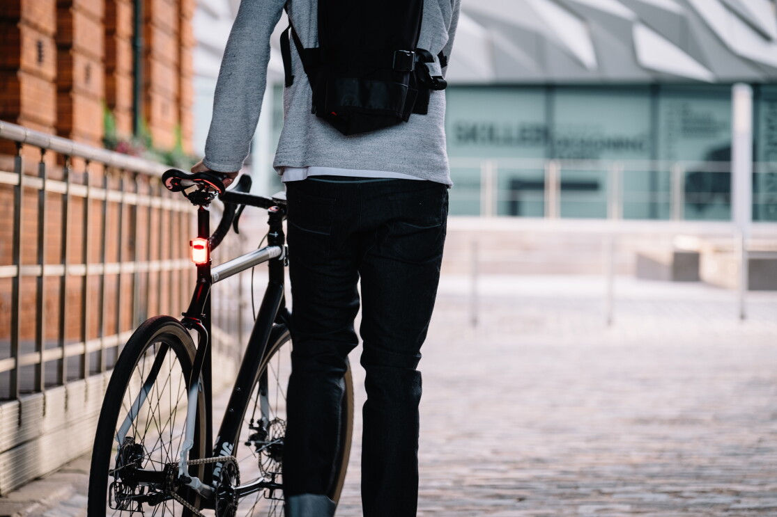 Cyclist stood with his back to camera holding a bike