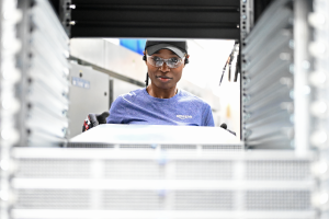 A photo of a data center technician behind a server rack.