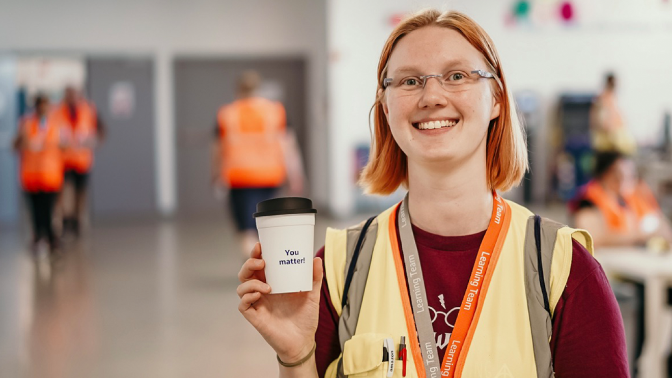 Eine Amazon Mitarbeiter hält einen Kaffeebecher mit de Aufschrift "You matter!"