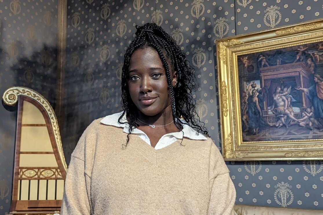 A black girl standing in front of a painting
