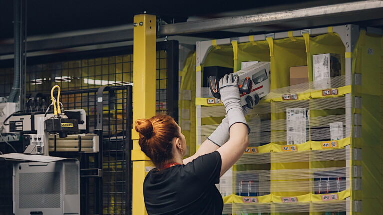An image of a woman adding an item to a small cubby on a large, yellow storage pod.