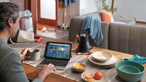 search words in presentations looking over a man's shoulder as he sits at a dining table covered in plates, a kettle, and table runner. he is browsing his fire max 11 tablet with a keyboard accessory