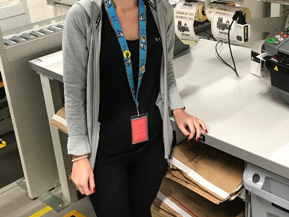 Shannon Willet, FC Associate standing at her table in a fulfilment centre.