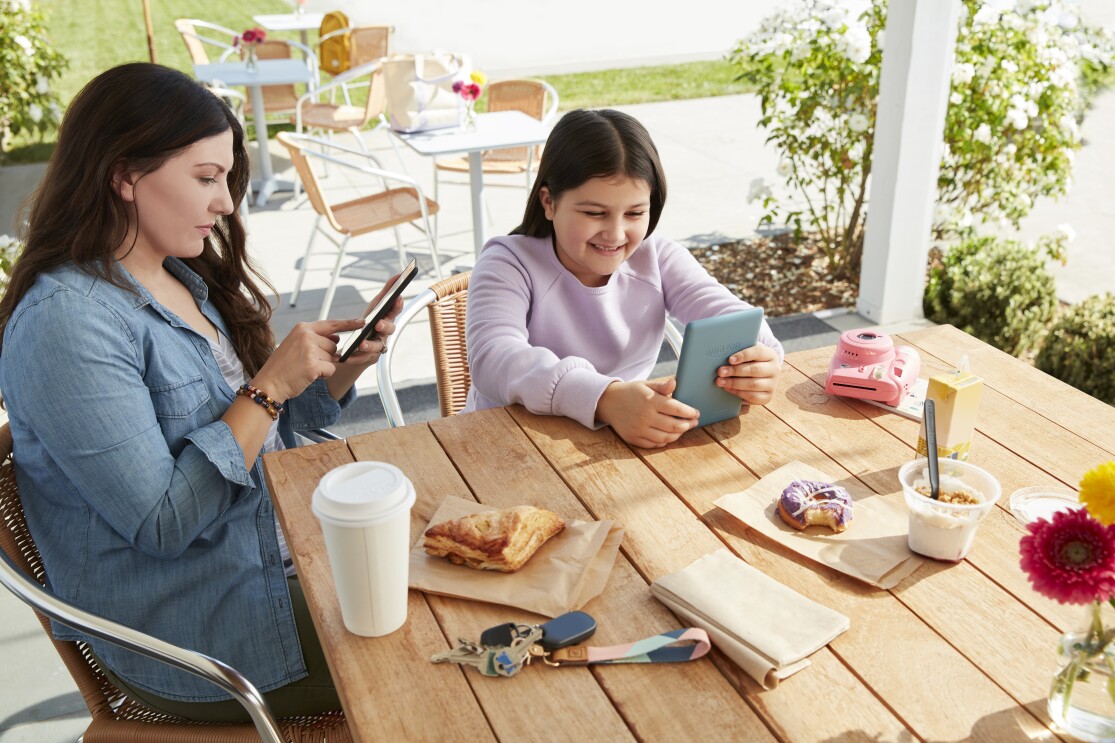 Mother and daughter sitting at outdoor dining table viewing their own devices.