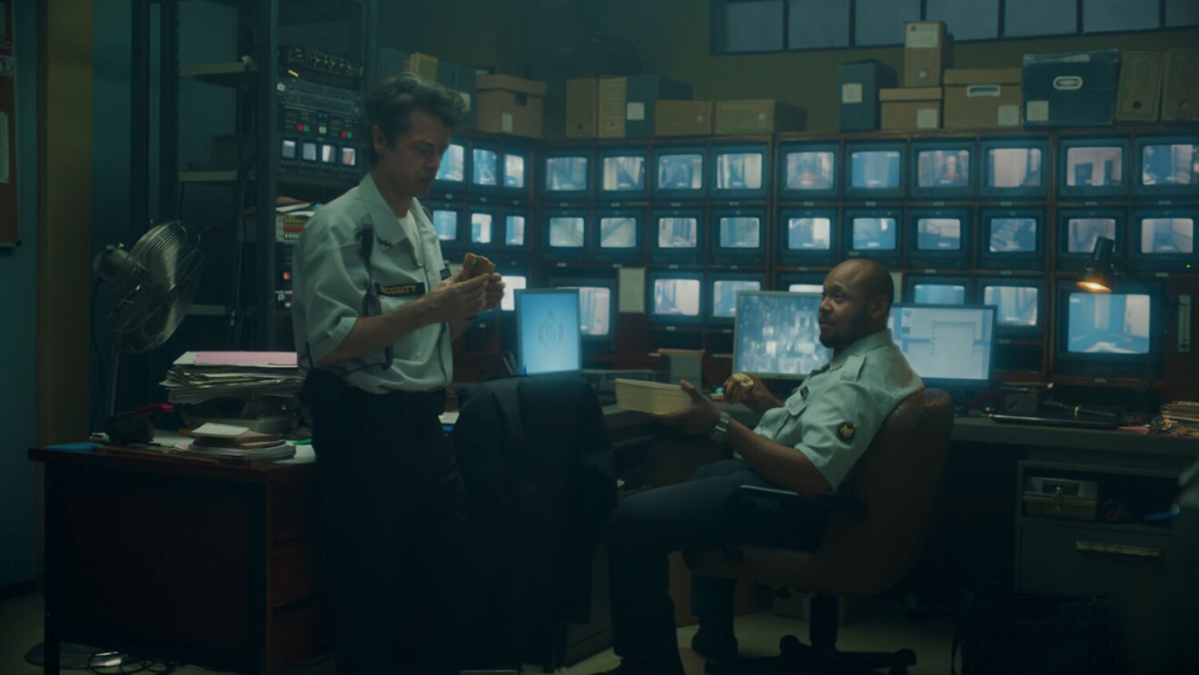 An screenshot image of a security guard in the security office during the Amazon Prime commercial where he becomes a chef. 