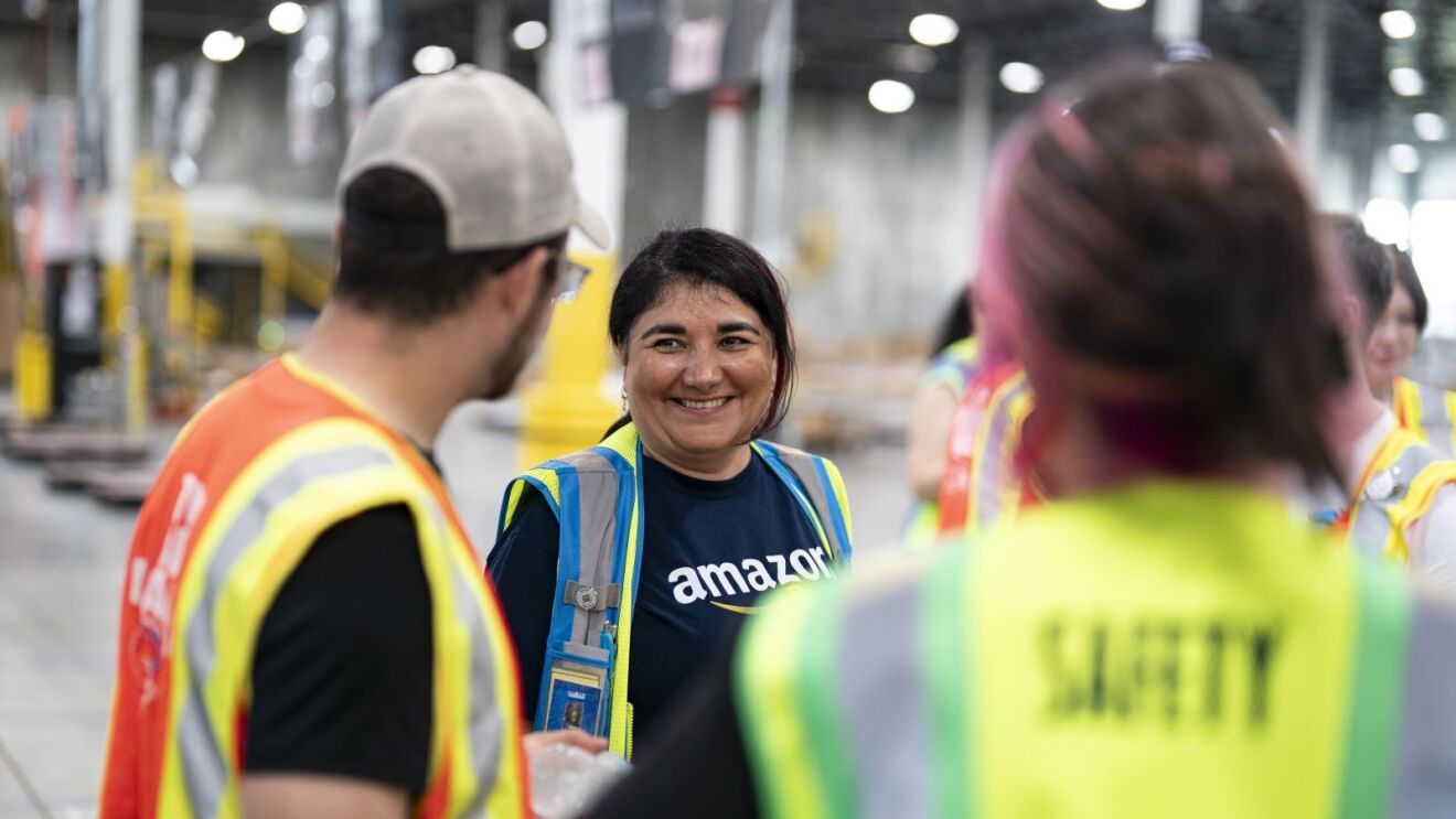 Amazon employee smiling with coworkers in facility