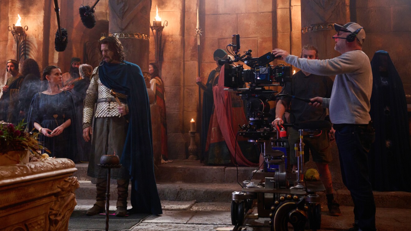 Medieval film set with actors and camera crew in stone hall