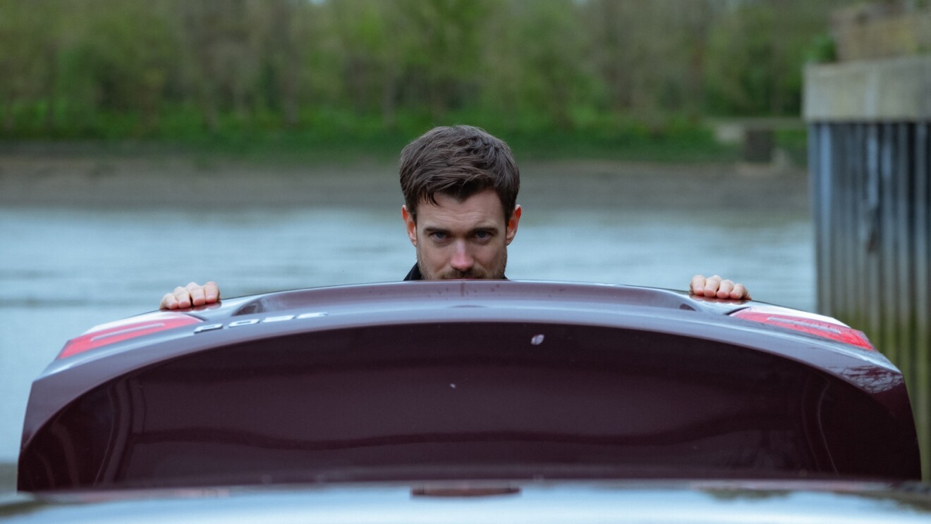 Man emerging from submerged car in lake
