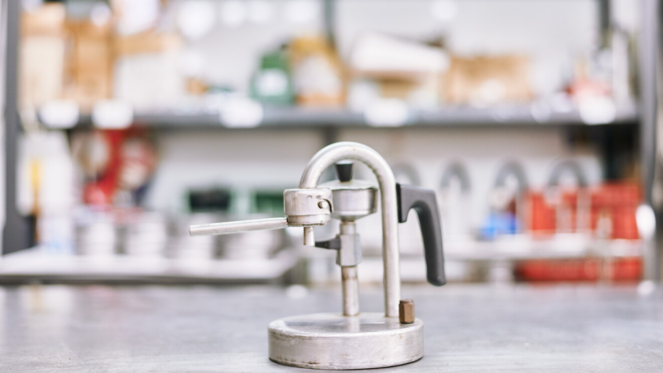 Foto di un prototipo molto essenziale di caffettiera Kamira. Manca quasi del tutto il serbatoio d'acqua, ma la linea a U invertita, il manico e l'erogatore si trovano già nella posizione che sarà quella della macchina finita.