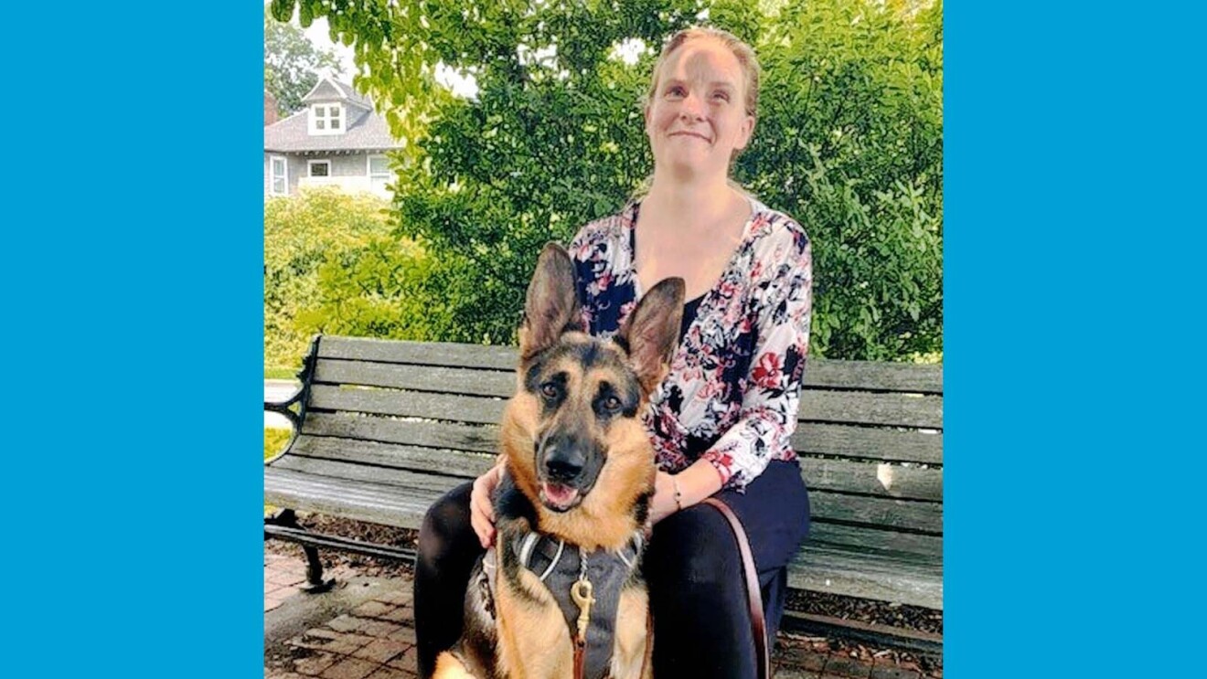 Jessie sitting on a bench with her German Shephard guide dog, Danica, in front of her.