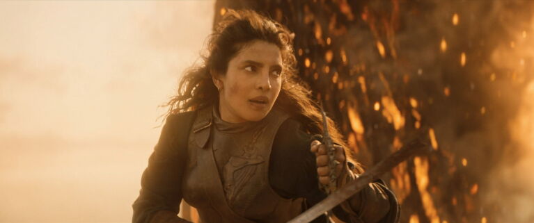 A woman holding a bow and arrow in orange lighting