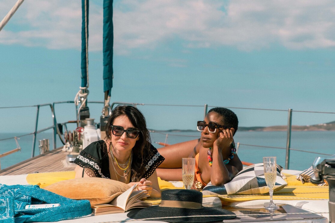 Two women lounge on a boat in the middle of the ocean